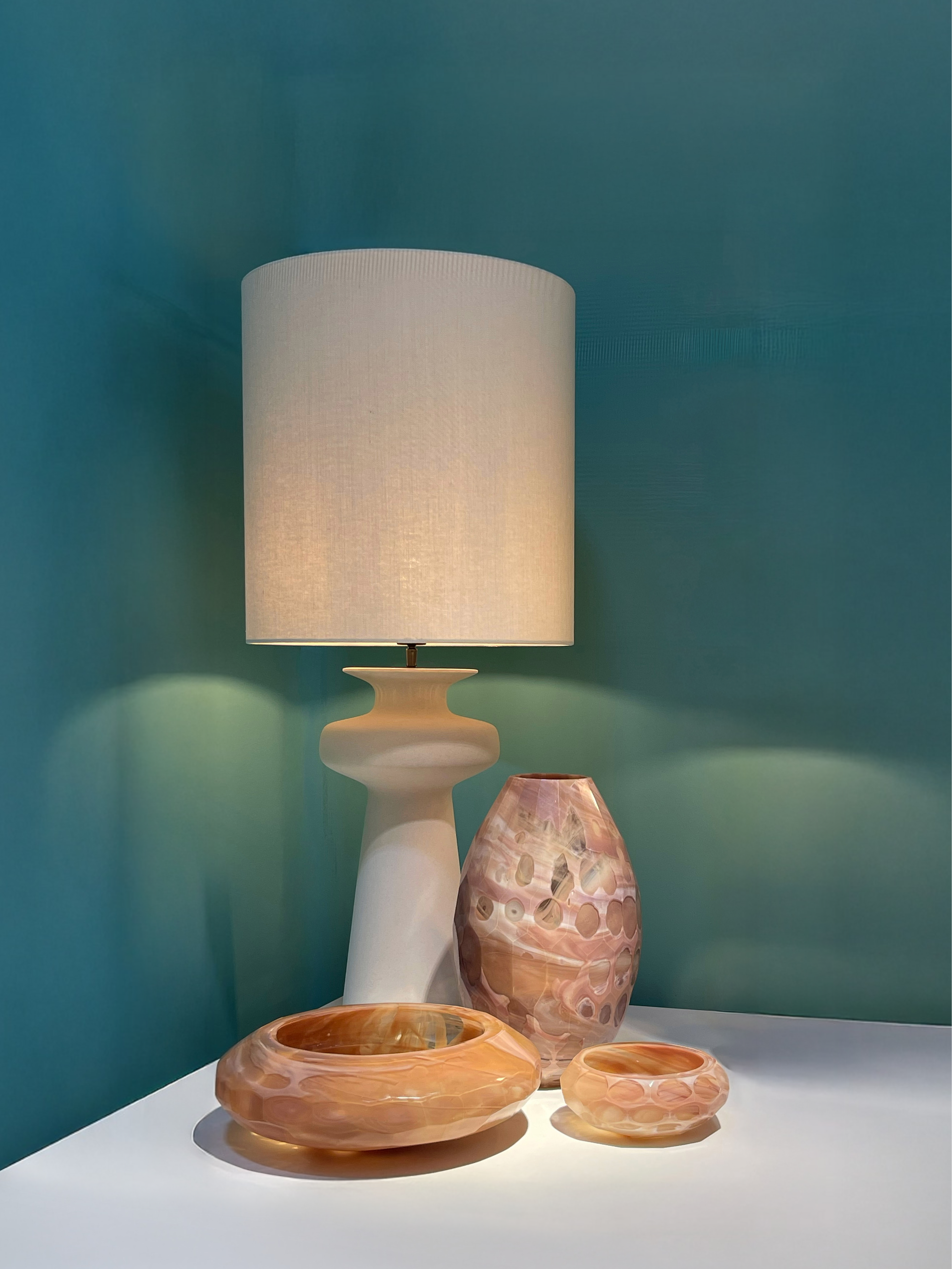 Sfeervol interieurbeeld met tafellamp en glazen objecten in warme tinten