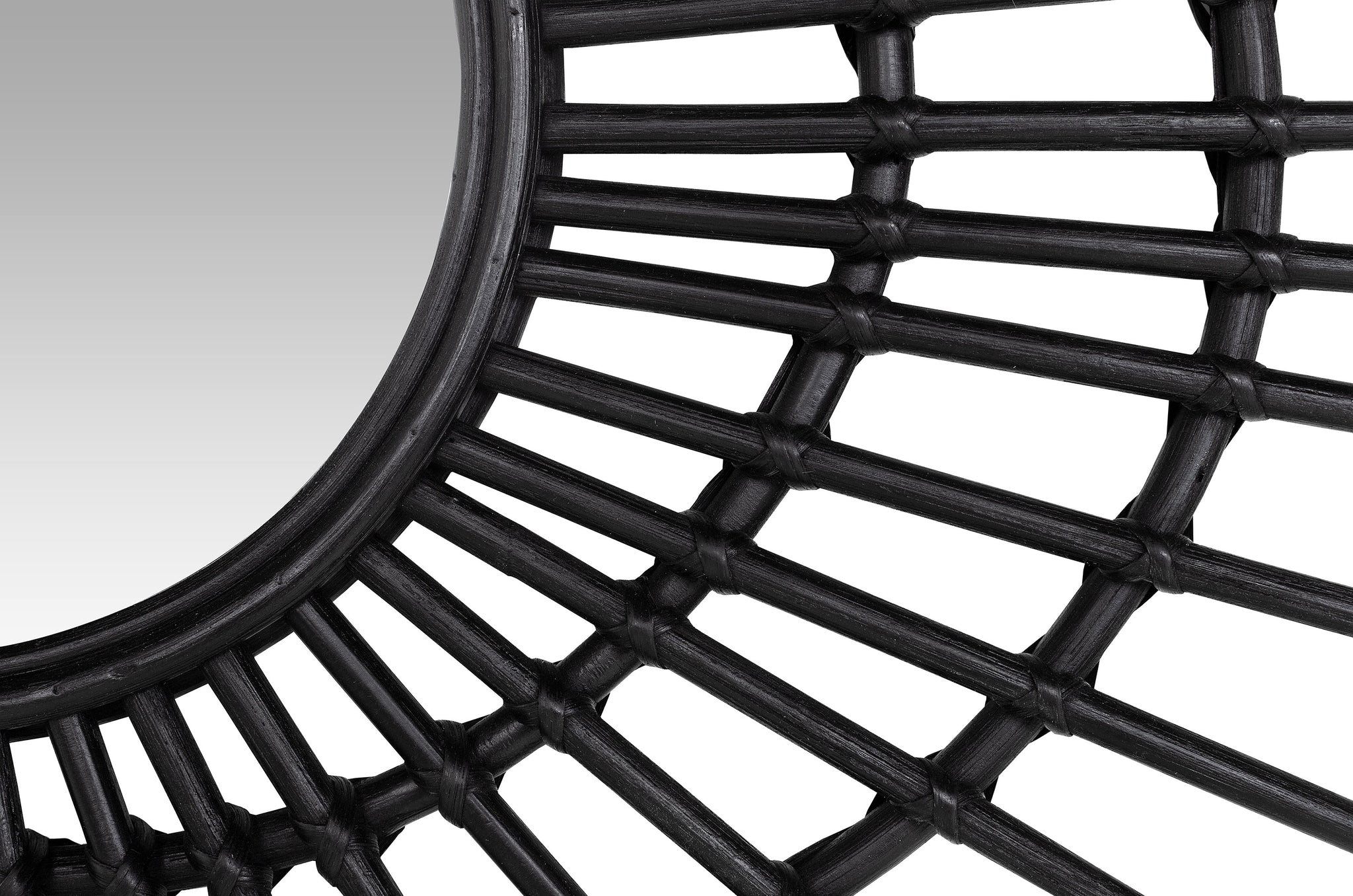 Zwarte wandspiegel van rotan met speels uitstralende stokken.